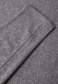 Grijze gebreide stof met een gladde textuur, voorzien van subtiele patroon details en kleine decoratieve strass steentjes langs de rand.