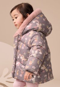 Veste matelassée gris clair avec des imprimés animaux et floraux pastel. Dotée d'un col en fausse fourrure rose et d'une fermeture éclair frontale.
