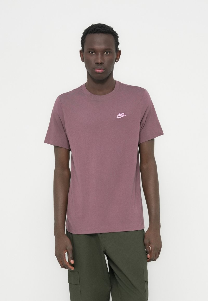 Μπλούζα με κοντά μανίκια και στρογγυλή λαιμόκοψη από βαμβάκι σε μπορντό χρώμα με μικρό ροζ λογότυπο Nike στο στήθος· σε συνδυασμό με πράσινο παντελόνι cargo.