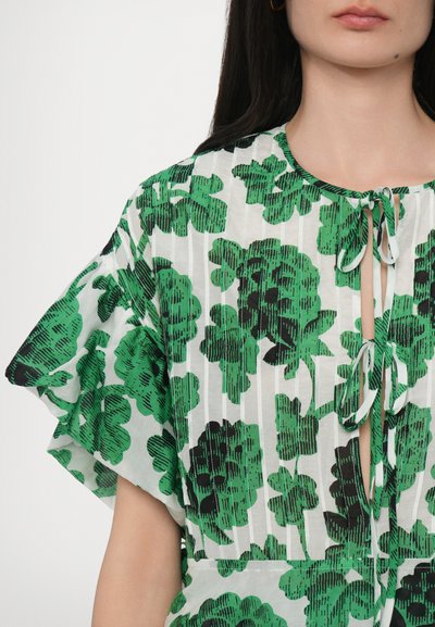 Green floral-patterned blouse with ruffled sleeves and a keyhole neckline, made from lightweight fabric with vertical stripes in the background.