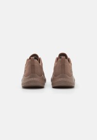 Brown athletic shoes with textured mesh upper, padded collar, and flexible outsole, featuring a logo on the side and pull tab on the heel.