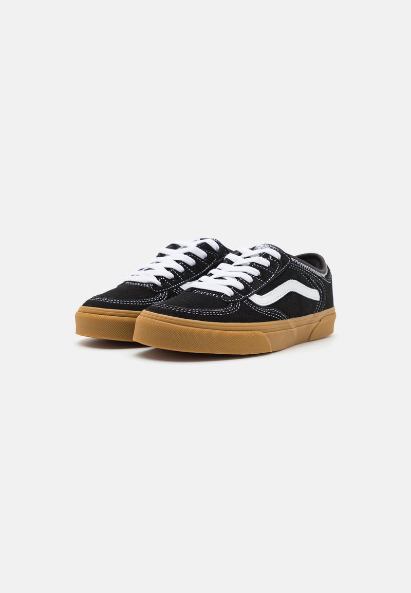 Zapatillas de ante negras con cordones blancos y una franja lateral blanca. Cuentan con una suela de goma texturizada y costuras blancas en contraste.