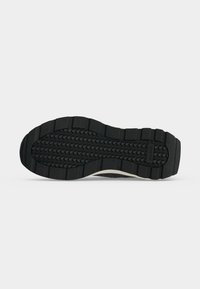 Semelle de chaussure en caoutchouc noir avec un motif de bande de roulement texturé et le nom de la marque ALDO embossé près du talon.