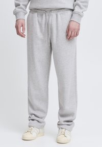 Gray cotton sweatpants with an elastic drawstring waist, side pockets, and a relaxed fit. Paired with white athletic shoes.