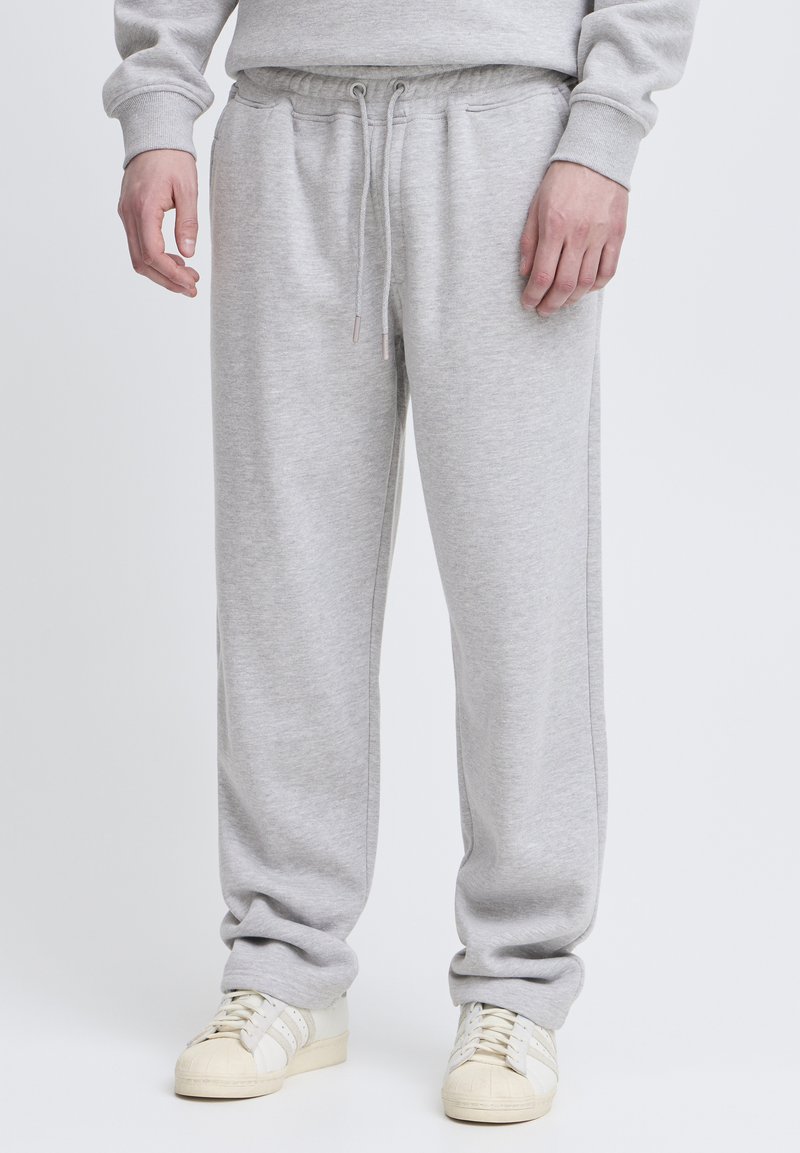 Gray cotton sweatpants with an elastic drawstring waist, side pockets, and a relaxed fit. Paired with white athletic shoes.