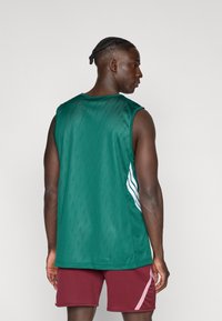Green mesh basketball jersey with a scooped neckline. Features three white stripes on the side and a loose fit. Worn with maroon shorts.