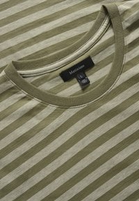 Camiseta a rayas verde y crema con cuello redondo, material de algodón y una etiqueta que indica tamaño L. Textura suave, diseño minimalista.