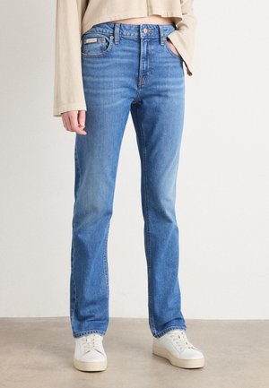 Lichtblauwe denim jeans met een recht model, contrasterende stiksels en een klein Calvin Klein label aan de tailleband. Gecombineerd met witte sneakers.