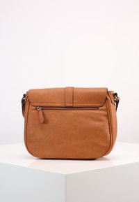 Ruskea nahkainen olkalaukku, jossa on suorakulmainen muoto, etuohjauskansi ja päällinen vetoketju. Takana on vetoketjullinen tasku lisätilaa varten.