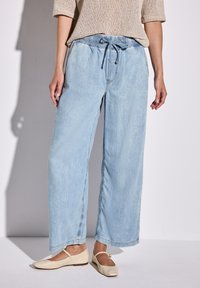 Hellblaue weit geschnittene Jeans mit elastischem Bund und Kordelzug. Hergestellt aus weichem Denim mit leicht ausgewaschenem Finish und geradem Saum.