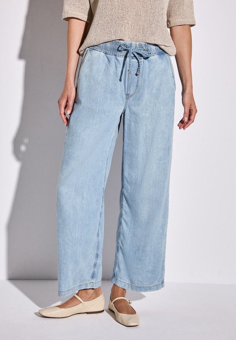 Hellblaue weit geschnittene Jeans mit elastischem Bund und Kordelzug. Hergestellt aus weichem Denim mit leicht ausgewaschenem Finish und geradem Saum.