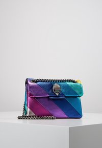 Kabelka z kůže v mnoha barvách s diagonálními pruhy v odstínech modré, fialové a žluté. Obsahuje stříbrný řetízkový popruh a dekorativní přihrádku.