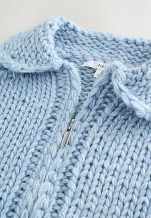 Lyseblå strikket sweater med krave, lynlås og grov struktur. Har ribmønstre og synlige syninger.