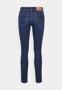 Vaqueros de denim azul de corte ajustado con cintura de altura media, dos bolsillos traseros y una etiqueta de cuero con marca en la cinturilla.