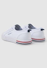 Sneakers bianchi in tela con punta rotonda, design elegante e accenti a righe rosse e blu navy contrastanti sulla suola. Logo ricamato sul lato.