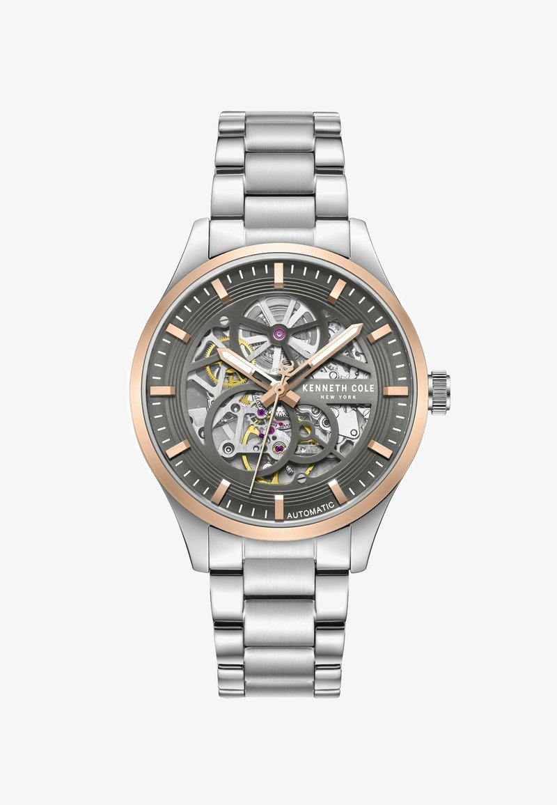 Szkieletowy zegarek automatyczny z srebrną bransoletą ze stali nierdzewnej, szarym cyferblatem z złotymi akcentami oraz odkrytymi detalami mechanizmu.