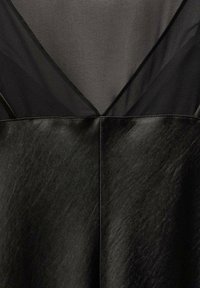 Schwarzes Kleid mit einem mehrschichtigen Design, das unten eine glatte, satinähnliche Textur und oben ein durchsichtiges Material aufweist. Auffälliger V-Ausschnitt.