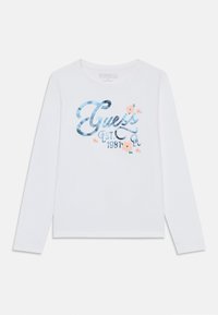 Long-sleeve white cotton t-shirt featuring a shiny blue graphic with "Guess Est. 1981" and floral accents in pink and green.
