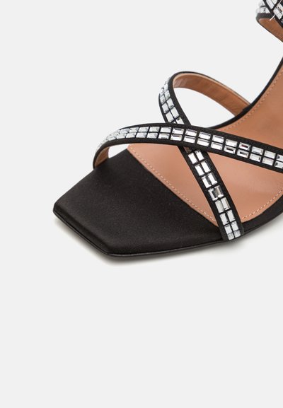 Pantofii din satin negru cu curea la gleznă au vârful pătrat, iar curelele se încrucișează fiind decorat cu mici cristale clare în formă pătrată.