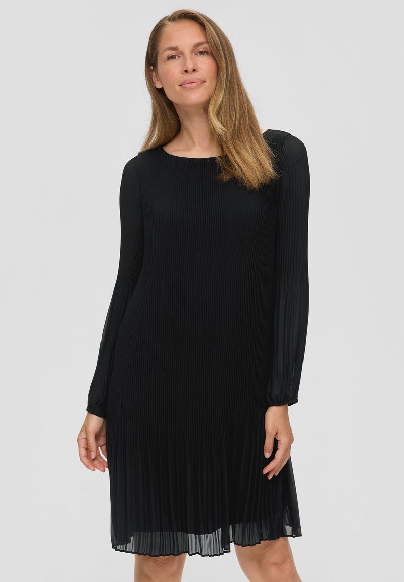 Schwarzes plissee Kleid mit langen Ärmeln, Rundhalsausschnitt und strukturiertem Stoff. Fließender Saum, der über dem Knie endet. Glattes, leichtes Material.