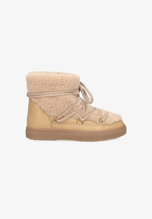 Beige Ankle Boots mit weichem Lammfell-Obermaterial, Schnürverschluss und einer tanfarbenen Gummisohle, entworfen für Komfort und Wärme.