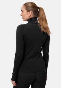 Pull noir à manches longues en tissu doux avec un col montant et des coutures plates, design ajusté et manches cintrées.