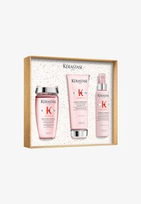 Il set di prodotti per la cura dei capelli Kérastase Genesis è composto da tre bottiglie rosa: uno shampoo, un balsamo e uno spray, presentati in una scatola a macchie dorate e bianche.