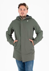 Giacca impermeabile verde con cappuccio zip, tasche frontali e logo sul petto. Tessuto liscio e design a taglio dritto.