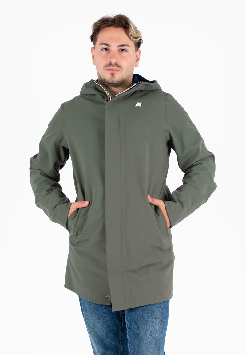 Giacca impermeabile verde con cappuccio zip, tasche frontali e logo sul petto. Tessuto liscio e design a taglio dritto.