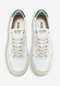 Coppia di sneaker Autry Medalist bianche con dettagli in camoscio beige, punta con fori, lacci beige e linguette verdi sul tallone, viste dall'alto.