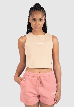 Beige korte tanktop met een wit logo en roze ontspannen shorts met een elastische tailleband en trekkoord, soepel stoftextuur.
