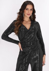 Schwarzer Pailletten-Jumpsuit mit langen Ärmeln, V-Ausschnitt und gerafftem Taillendetail. Verfügt über ein schlankes, tailliertes Design und einen schimmernden Stoff.