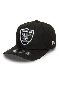 Black baseball cap made of fabric, featuring an embroidered Raiders logo on a shield patch, with a flat brim and logo sticker on peak.