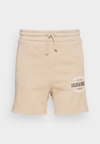Béžové bavlněné šortky s elastickým pasem, šňůrkou, bočními kapsami a potiskem loga. Základní design s jemnou texturou.