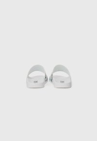White slide sandals with a smooth finish, featuring a floral pattern in blue and green on the sides. Open heel and toe design.