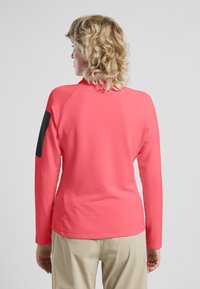 Langarmhemd in leuchtendem Pink, mit strukturiertem Muster und einem kontrastierenden schwarzen Akzent auf der linken Schulter. Rückansicht gezeigt.