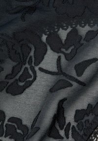 Tessuto a fantasia floreale nera con una superficie textured, caratterizzato da disegni floreali scuri in rilievo su uno sfondo grigio sottile.