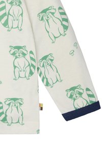 Baumwollbekleidung mit einem cremefarbenen Hintergrund und grünen Waschbär-Illustrationen. Am Ende der Ärmel mit einem dunkelblauen Bündchen akzentuiert.