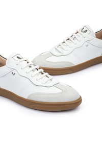 Witte sneakers met een getextureerde suède neus, gladde leren zijpanelen en een rubberen gumzool. Inclusief witte veters en een logo op de tong.