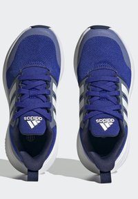 Niebieskie buty sportowe z siateczkową cholewką, białymi akcentami i szarymi detalami. Posiadają sznurówki, wyściółkę w kołnierzu oraz gumową podeszwę dla lepszej przyczepności.