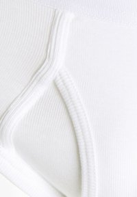 Hvide ribbede bomuldsunderbukser med ensartet tekstur, elastisk talje, og sømdetaljer langs siderne for en struktureret pasform.