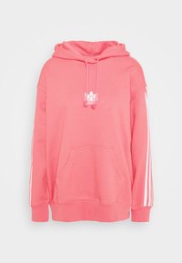 Růžová mikina s kapucí vyrobená z měkké látky, s přední kapsou, bílým logem a bílými pruhy po stranách rukávů. Nastavitelná kapuce se stahovací šňůrkou.