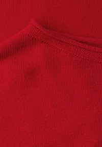 Czerwona dzianina o gładkiej fakturze, z delikatnym paskowanym wzorem na krawędziach. Miękki i giętki materiał.