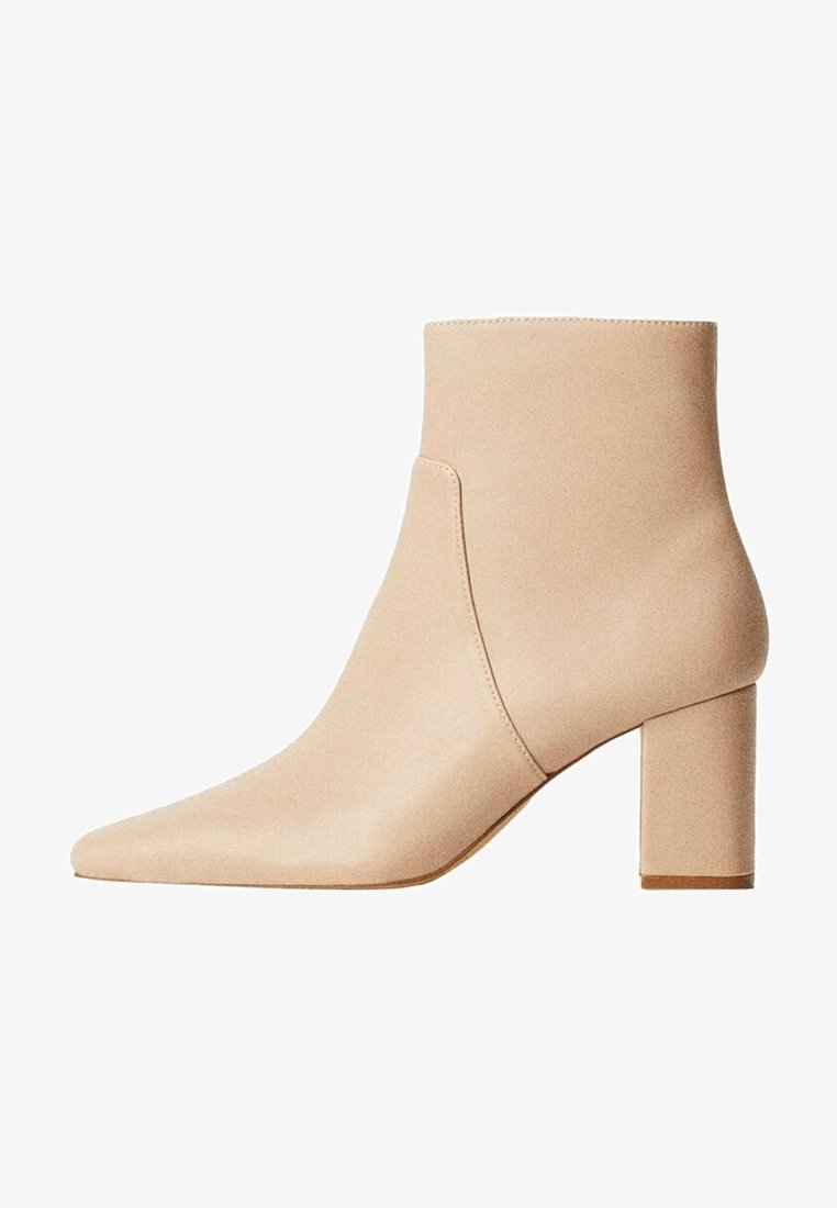 Bottine en cuir beige avec bout pointu et talon bloc épais, détail de couture latérale, texture lisse et design minimaliste.