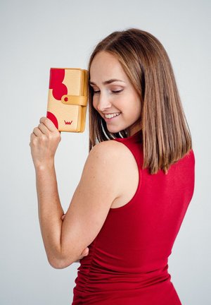 Yellow wallet with red abstract patterns, featuring a snap closure and visible logo. Smooth texture, compact rectangular shape.