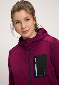 Veste en polaire de couleur violet profond avec une capuche ajustée, poche zippée noire avec une fermeture éclair bleu clair et des détails en relief.