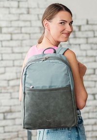 Grau und hellblauer Rucksack mit verstellbaren Trägern, einer Fronttasche, weichem Material und einem glatten Reißverschluss.