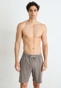 Grå bomullsshorts med elastisk linning og snor. Enkel design, kne-lengde, glatt tekstur, uten ekstra mønstre eller detaljer.