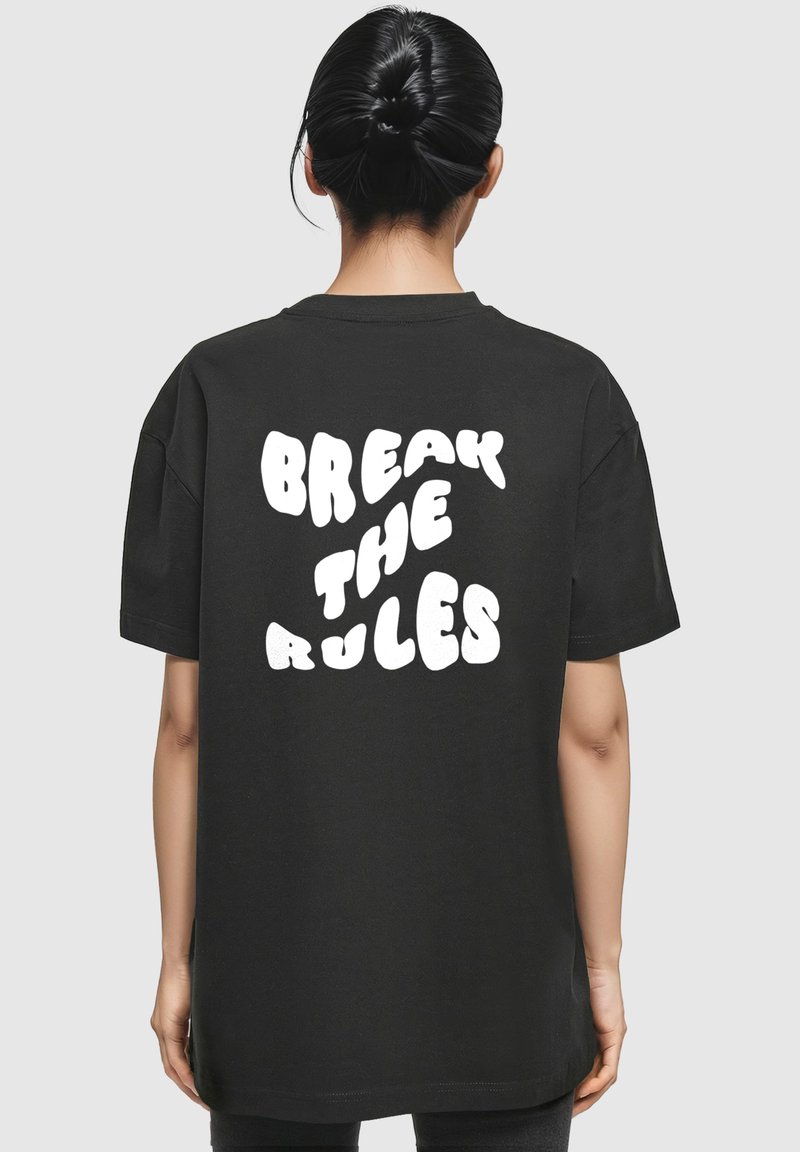 Sort oversized t-shirt med hvid boblet tekst på ryggen, der står "BREAK THE RULES." Korte ærmer og crew neck design.