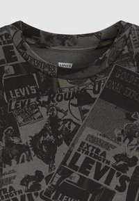 Μαύρο μπλουζάκι με κολάζ από παλιές διαφημίσεις και γραφικά, με ριμπ ύφασμα γύρω από το λαιμό και απαλή υφή υφάσματος.